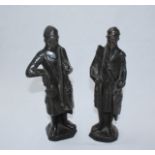 A pair of bronze figures of men dressed in Medieval style dress with swords and shields. Tallest