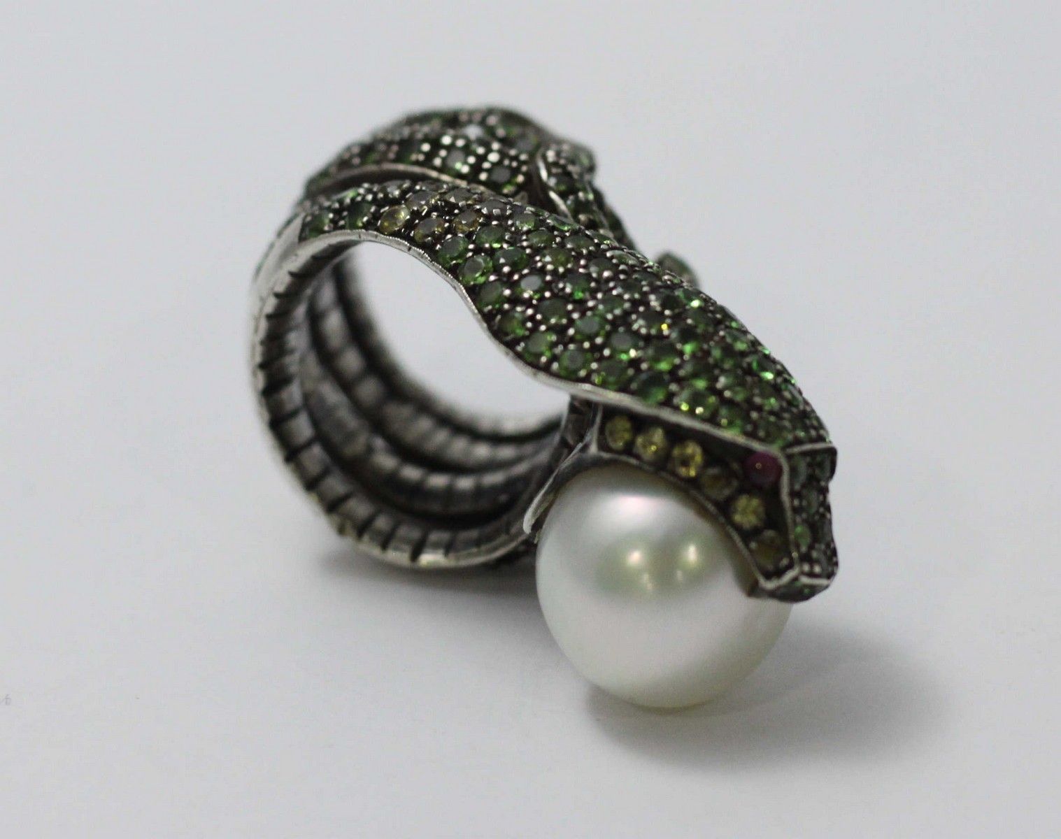 A white-metal ring modelled as a coiled snake, pave-set with green stones and holding a large - Image 4 of 5