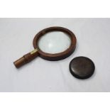 A plain circular burr wood snuff box, 8cm diameter, together with a wooden magnifying glass.