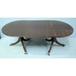 A 20th century mahogany dining table, the solid mahogany top with additional leaf and raised on