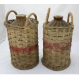 Two empty Royal Navy issue Pusser's Rum wicker-cased stoneware one-gallon bottles, with red paint