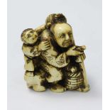 A Japanese Meiji Period Carved and stained Ivory Netsuke figure of an elderly man with a staff,