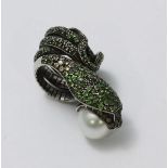 A white-metal ring modelled as a coiled snake, pave-set with green stones and holding a large