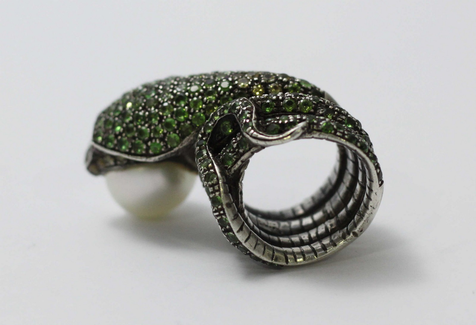 A white-metal ring modelled as a coiled snake, pave-set with green stones and holding a large - Image 3 of 5