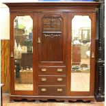 A Edwardian stained walnut triple wardrobe with central short door above three graduated drawers,