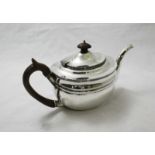 A silver teapot by Charles Stuart Harris with stained fruitwood handle and finials. Hallmarked