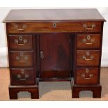 A mahogany kneehole desk, in eighteenth century style , the frieze drawer above a recessed