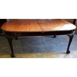 An Edwardian mahogany extending dining table, the rectangular top with bowed ends and fitted three