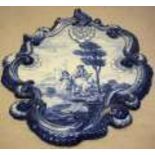 A Dutch blue and white wall plaque, the rococo cartouche shape decorated a couple journeying with