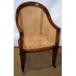 A William IV faded mahogany frame bergere, with caned panels and seat, on front turned legs to brass
