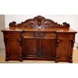 An early Victorian mahogany sideboard, the inverted breakfront top with a scrolling foliage carved