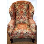 A wing armchair in early eighteenth century style, with a floral loose cover, the cushion seat on
