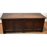 A seventeenth century oak coffer, the moulded edge plank top on iron hinges, the four panel front