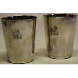 A pair of George III silver beakers, the tapering sides engraved a chained lion rampant crest,