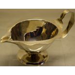 A large Arts and Crafts hammered oval silver sauceboat, with a wavy rim and loop handle, a rope