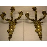 A pair of French ormolu cast rococo three light wall sconces, with sprays of foliage, the three