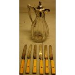 An Edwardian glass claret jug, the cut panelled pear shape body with a silver mounted neck, a scroll