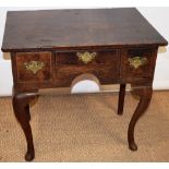 A mid eighteenth century oak lowboy, the shaped frieze with three drawers, fitted brass plate