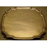 A square silver salver, with a shaped raised border, the concave corners on claw and ball feet, 12in