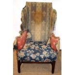 An eighteenth century wing armchair, the upholstery with remains of red patterned floral material,