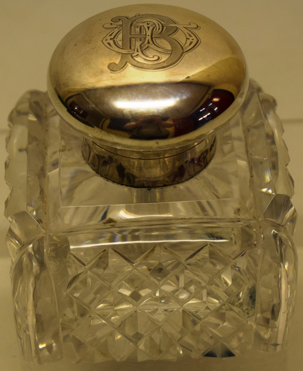 A George V cut glass square inkwell with mounted glass pen dip, having a hinged silver lid