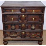 A Charles II oak chest of four long drawers, the linings on side runners having geometric panelled