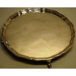 A circular silver salver, with a raised serpentine moulded border, on four hoof feet, 10in (25.