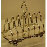 A Victorian silver toast rack, the seven divisions of arc doublet shape with a central handle, on