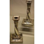 A pair of Edwardian silver candlesticks, the stems entwined with boughs of acorns and leaves, having