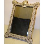 A late Victorian toilet mirror, the padded easel back with an applied silver front, pierced with