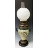 A Doulton Lambeth oil lamp of two handled urnular form relief moulded with prunus blossom,