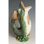 A Majolica fish jug of conventional form on circular green and brown base, 27cm high,
