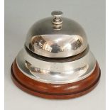 A silver desk or counter bell, twist action button to top, conventional domed shape,