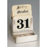A silver perpetual desk calendar, the plain body with demi-lune pen rest to base,