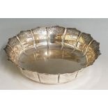 A silver dish, the petal form scalloped sides chased with a repeating scroll motif,