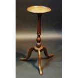 A mid 18th Century oak candle stand the circular dished top with moulded rim above a slender column