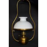 A Victorian brass framed hanging oil lamp with opaque white glass shade,