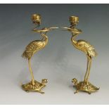 A pair of Japanese bronze candlesticks modelled as storks with snakes in their mouths supporting