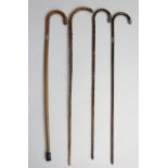 A collection of four crook handled walking sticks, all with silver mounts and/or collars,