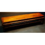 A Chinese hardwood long bench or table the rectangular top above a shaped frieze with pierced