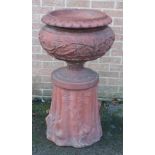 A Victorian terracotta garden urn with stylised leaf moulded rim the compressed body relief moulded