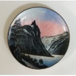 A circular enamelled silver dish the engine turned ground enamelled with stylised mountains,