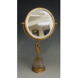A gilt metal and glass dressing table mirror the circular bevelled plate revolving in a U-shaped