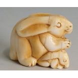 A Japanese ivory netsuke carved as a rabbit and kitten, 3.