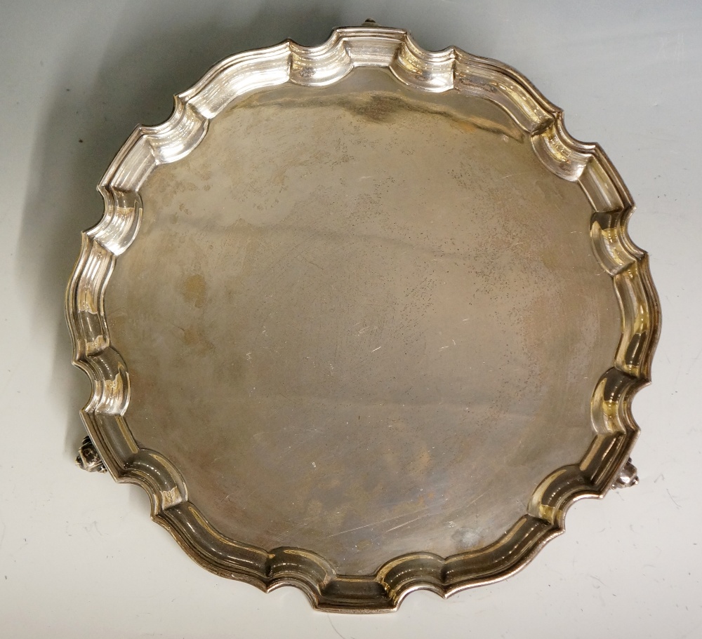 A plain silver salver with pie crust style edging, three ball and claw feet,