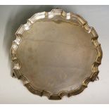 A plain silver salver with pie crust style edging, three ball and claw feet,