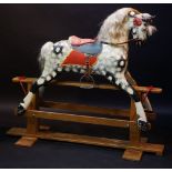 A carved wooden rocking horse, dapple grey, with upholstered seat,