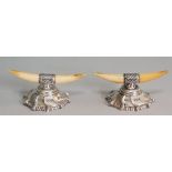 A pair of silver mounted polished bone knife rests, stepped spirally embossed circular feet,