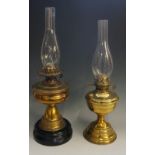 A Victorian brass oil lamp with black pottery base, duplex burner, glass chimney,