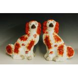 A pair of Staffordshire pottery spaniels detailed in iron red with painted eyes and snouts,